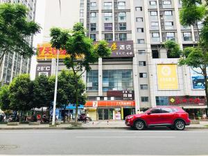 una macchina rossa parcheggiata sul lato di una strada cittadina di 7Days Premium Chengdu Pi County Xiqu Avenue Branch a Chengdu