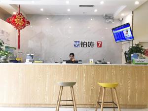 Una donna seduta al bancone con un portatile di 7Days Premium Chengdu Pi County Xiqu Avenue Branch a Chengdu