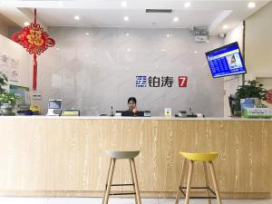 a woman sitting at a counter with a laptop at 7Days Premium Chengdu Pi County Xiqu Avenue Branch in Chengdu