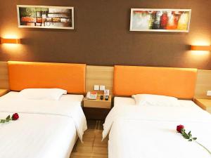 two beds in a hotel room with flowers on them at 7Days Premium Chengdu Pi County Xiqu Avenue Branch in Chengdu