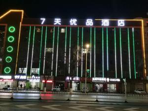 duży budynek z zielonymi światłami w nocy w obiekcie 7Days Premium Yinchuan High Speed Railway Station Train Station Branch w mieście Yinchuan