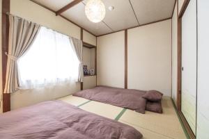 dwa łóżka w pokoju z oknem w obiekcie Mibusanjo Guesthouse w mieście Kioto