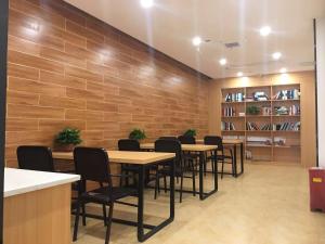 une salle à manger avec des tables, des chaises et un mur dans l'établissement 7Days Premium Changsha Environmental Science and Technology Park University of Technology Yuntang Campus Branch, à Changsha