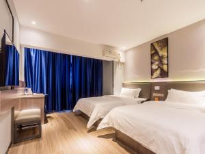 two beds in a hotel room with blue curtains at 7Days Premium Zhongshan Tanzhou Town Market Central Branch in Zhongshan