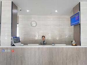 a man giving a speech at a counter in an office at 7Days Premium Jiyuan Tiantai Road Xinyao City Square Branch in Jiyuan