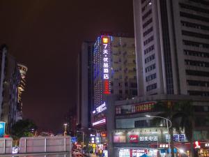 un edificio iluminado en una ciudad por la noche en 7 Days Premium Jiangmen Diwang Plaza Branch en Jiangmen