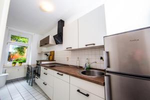 een keuken met een roestvrijstalen koelkast en een wastafel bij Ruhiges City Apartment "Altbauperle" mit Charme und 2 Schlafzimmern in Erfurt