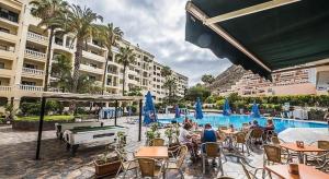 a group of people sitting around a pool at a hotel at Peaceful & Bright Loft, HEATED POOL, NETFLIX, FREE WIFI & PARKING, TENNIS in Los Cristianos