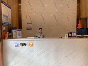 a man sitting at a counter in a room at 7Days Premium Shenzhen High Speed Rail North Station Minzhi Branch in Shenzhen
