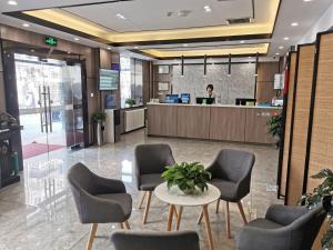a woman standing in a lobby with chairs and a table at 7Days Premium Tianjin Ancient Culture Street Tianjin Eye Branch in Tianjin