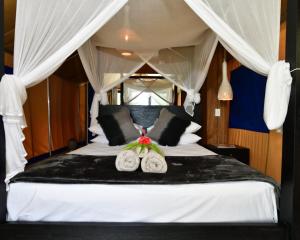 a bedroom with a white bed with two pillows at Turtle Bay Lodge in Luganville