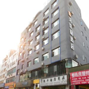 d'un grand bâtiment gris avec un panneau. dans l'établissement 7Days Premium Xingyi Pingdong Avenue Branch, à Xiawutun