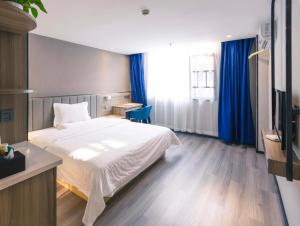 a bedroom with a white bed and blue curtains at 7Days Premium Xingyi Pingdong Avenue Branch in Xiawutun
