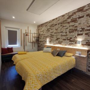 a bedroom with a yellow bed with a brick wall at Kukamona in O Pino 