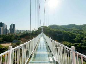 a suspension bridge over a river with a city in the background at 7Days Premium Dongguan Fenggang Yongsheng Street Branch in Tiantangwei