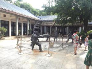 a group of people standing around a statue in a courtyard at 7Days Premium Dongguan Fenggang Yongsheng Street Branch in Tiantangwei