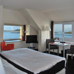 a hotel room with a bed and a table and chairs at Hotel Le Temps De Vivre in Roscoff