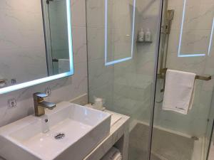a bathroom with a sink and a glass shower at 7Days Premium Yunfu Yunan Branch in Yunan