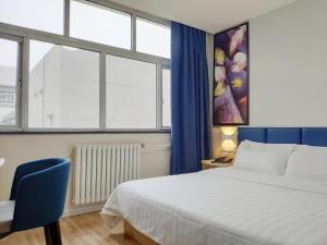 a bedroom with a bed and a blue chair and windows at 7Days Inn Xi'an Jiaoda Medical College Weiyi Street Subway Station in Xi'an