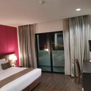 a hotel room with a bed and a large window at Coco View Hotel in Samut Songkhram