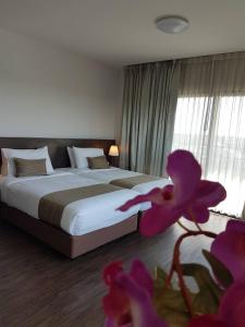 a bedroom with a large bed and a purple flower at Coco View Hotel in Samut Songkhram