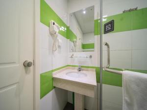 a green and white bathroom with a sink and a phone at 7Days Inn Taizhou Jiangyan Qintong Ancient Town in Taizhou