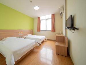 a bedroom with two beds and a flat screen tv at 7Days Inn Taizhou Jiangyan Qintong Ancient Town in Taizhou
