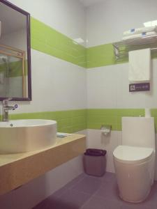 a green and white bathroom with a sink and a toilet at 7 Days Inn Foshan Pingzhou Jade Street Branch in Foshan