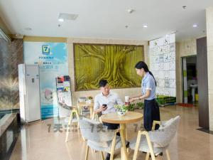 a woman standing next to a man sitting at a table at 7Days Inn Panyu Square Shilian Road Branch in Guangzhou
