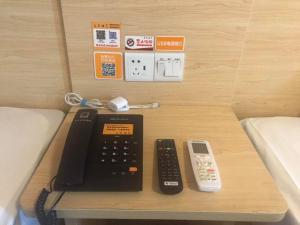 escritorio con calculadora y mando a distancia en 7Days Inn Enshi Railway Station Branch, en Longfengba