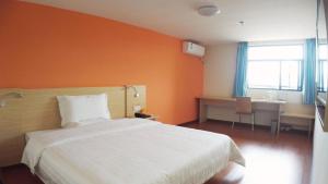 sypialnia z łóżkiem z pomarańczową ścianą w obiekcie 7Days Inn Enshi Railway Station Branch w mieście Longfengba