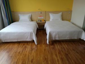 two beds sitting next to each other in a room at 7 Days Inn Wuzhishan Yanhe South Road Branch in T'ung-shih-shih