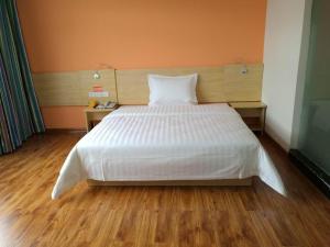 Schlafzimmer mit einem großen weißen Bett und Holzböden in der Unterkunft 7 Days Inn Wuzhishan Yanhe South Road Branch in T'ung-shih-shih