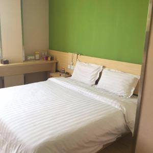 ein Schlafzimmer mit einem großen weißen Bett und einer grünen Wand in der Unterkunft 7Days Inn Ziyang Lezhi Yingbin Avenue Branch in Ziyang