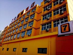 un grande edificio giallo con un cartello di fronte di 7 Days Inn Tianjin Jiaotong University Caozhuang Subway Station Branch a Tianjin