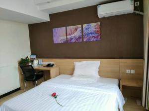 7Days Inn Yancheng Yingbin Avenue Engineering College Branch في يانتشنغ: غرفة نوم بسرير ابيض وعليه ورد
