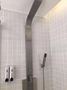 ein Bad mit einer Dusche und weiß gefliesten Wänden in der Unterkunft 7 Days Hotel Taixing Wenchang Road Branch in Taizhou