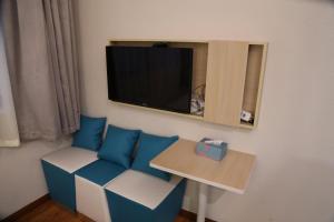a room with a couch and a tv on a wall at 7 Days Hotel Taixing Wenchang Road Branch in Taizhou