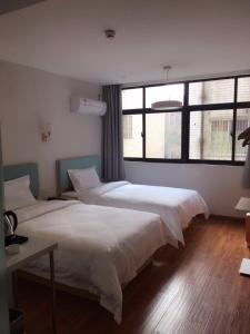 a bedroom with two beds and a large window at 7 Days Hotel Taixing Wenchang Road Branch in Taizhou