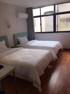 two beds in a room with two windows at 7 Days Hotel Taixing Wenchang Road Branch in Taizhou