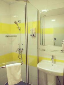 a bathroom with a sink and a glass shower at 7Days Inn Yibin Boxi City Center Branch in Yibin