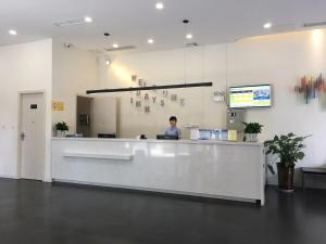 Un uomo in piedi davanti a un bancone in un atrio dell'ospedale di 7Days Inn Santai Zizhou Avenue Branch a Mianyang Altre 8 foto