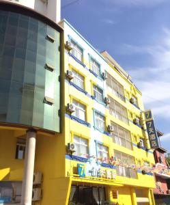 允景洪的住宿－7天酒店·西双版纳嘎洒机场客运南站店，黄色建筑,有玻璃幕墙