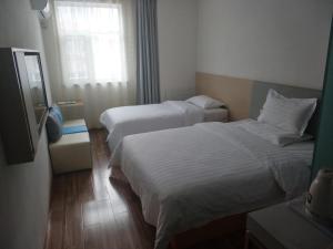 a hotel room with two beds and a window at 7 Days Hotel Urumqi Kashgar East Road Normal University Branch in Ürümqi