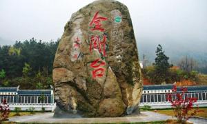 uma grande rocha com escrita em frente a um edifício em 7Days Inn Xinyang Mall North Bus Station em Shangcheng