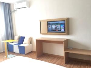 Habitación con cama y TV en la pared. en 7Days Inn Ganzhou Huichang Changshou Branch, 
