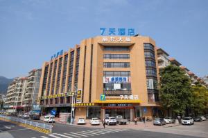 a large building with cars parked in front of a street at 7Days Inn Yunfu Jinshan Bus Intercharge Branch in Yunfu