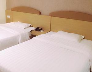 duas camas brancas num quarto de hotel com um telefone em 7Days Inn Wuchang Railway Subway Station em Wuhan
