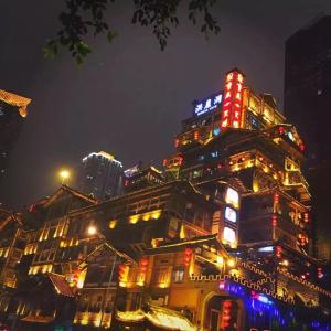 a building with neon lights on top of it at night at 7Days Inn Chongqing Longtou Temple North Train Station North Plaza Branch in Chongqing