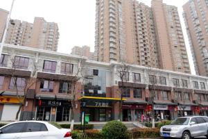 un edificio con coches estacionados frente a edificios altos en 7Days Inn Xuzhou Xincheng City Council Aoti Branch, en Xuzhou